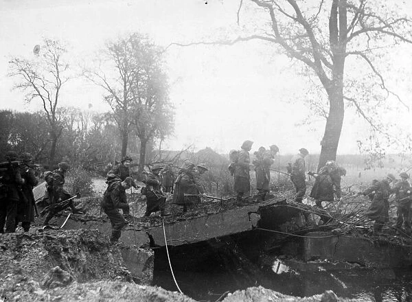 An Allied patrol moves across a damaged bridge over the River Meuse near Broekhuizen
