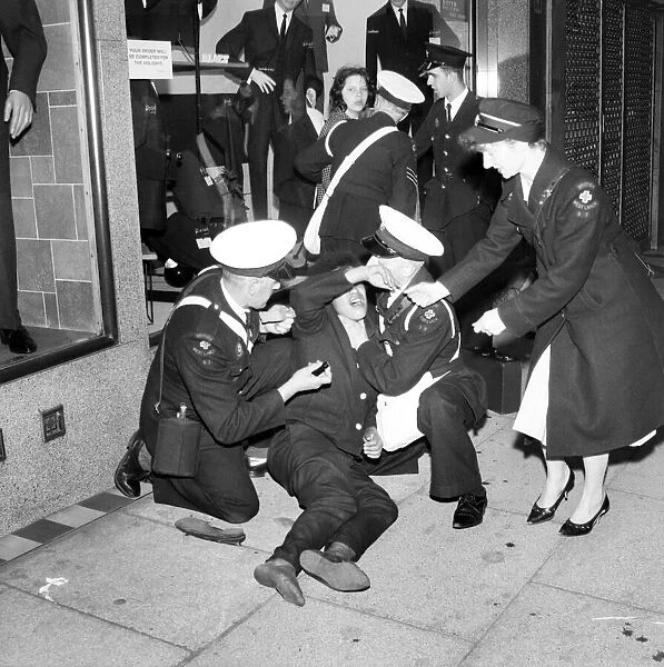 Ambulance men and medical workers attend to a Beatles fan who was injured in a crush as