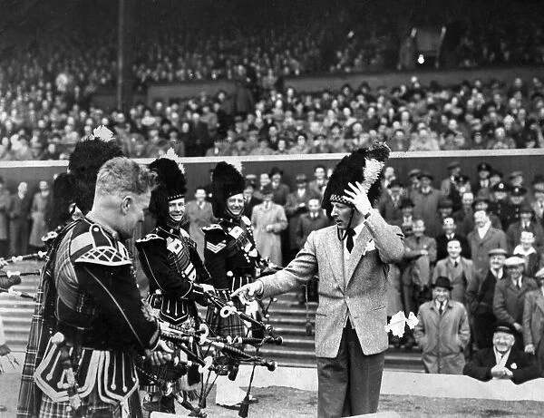 American actor and comedian Danny Kaye, complete with busby puts the Pipe band through