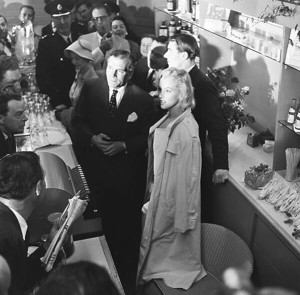 American actress Marilyn Monroe and Sir Laurence Olivier seek refuge from the waiting