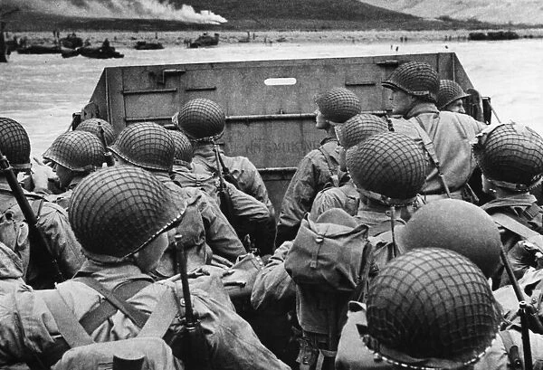 American assault troops in landing craft huddle behind the protective front of the craft