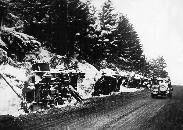 American and German military vehicles lie overturned on the roadside after being put out