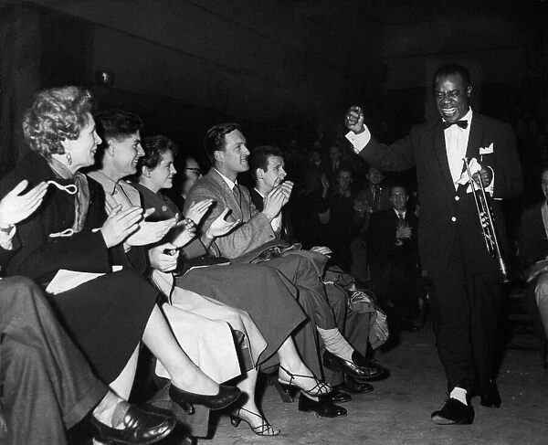 American jazz musician Louis Armstrong acknowledges the cheers of the fans as he enters