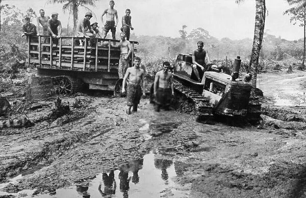 American marines with a caterpillar tractor and trailer move ahead through a sea of mud