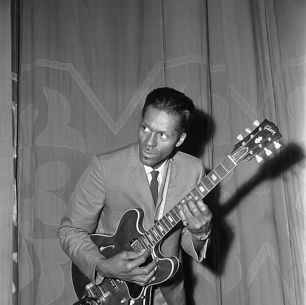 American rock and roll singer and musician Chuck Berry tunes up his guitar before going