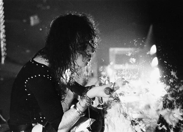 American rock singer Alice Cooper blows feathers nto the crowd during a concert in London