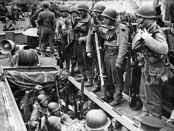 American soldiers laden with equipment and weapons assemble on board a small landing