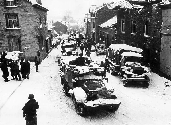 American tanks and infantrymen on their way up to the front pass through the street of