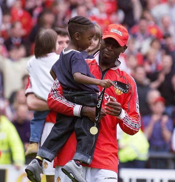 Andy Cole Manchester United footballer May 1999 celebrating carrying his young son