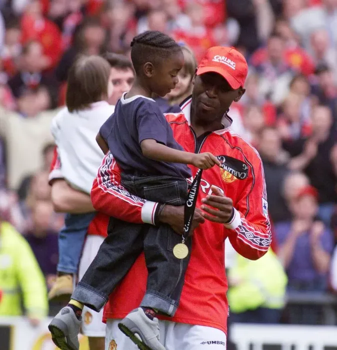 Framed Print : Andy Cole Manchester United footballer May 1999 celebrating carrying his young son Framed Print : Andy Cole Manchester United footballer May 1999 celebrating carrying his young son