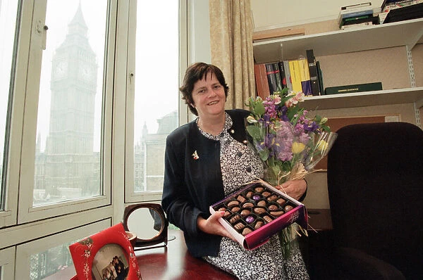 Ann Widdecombe in her Perliament office holding flowers and a box of chocolates