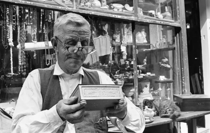 Framed Print : An antique dealers inspects his goods at his shop in The Lanes in Brighton July Framed Print : An antique dealers inspects his goods at his shop in The Lanes in Brighton July