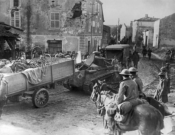 Two US Army calvalrymen seen here watching a Renault FT light tanks towing a truck loaded