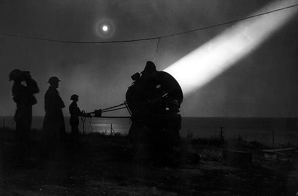 An army search light crew scans the night sky for enemy aircraft during WW2