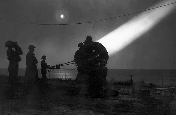 An army search light crew scans the night sky for enemy aircraft during WW2