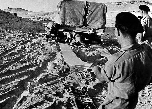 Eight Army soldiers using mats to release a lorry trapped in soft sand in Egypt 1942 WW2
