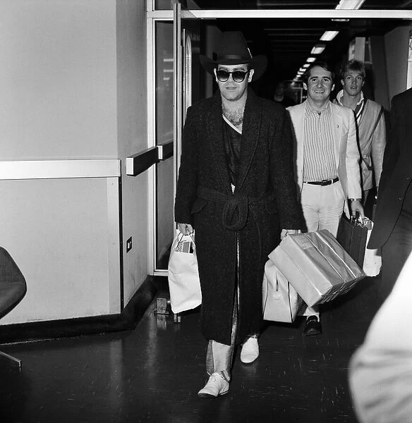 The arrival of Elton John at Heathrow Airport carrying Christmas presents from a buying