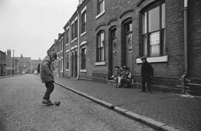 Framed Print : Two asian boys playing football in the street while their friends look on in Marshall