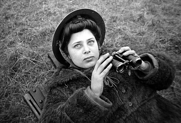 An ATS woman using a pair of binoculars on searchlight Battery January 1943