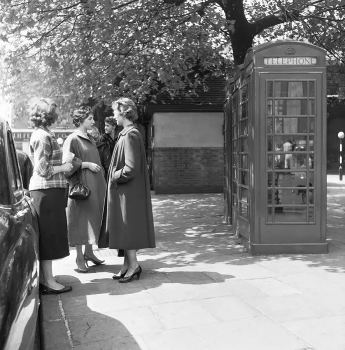 Framed Print : awaiting their turn. Ladies queue to use the public telephone box close to the Tower of