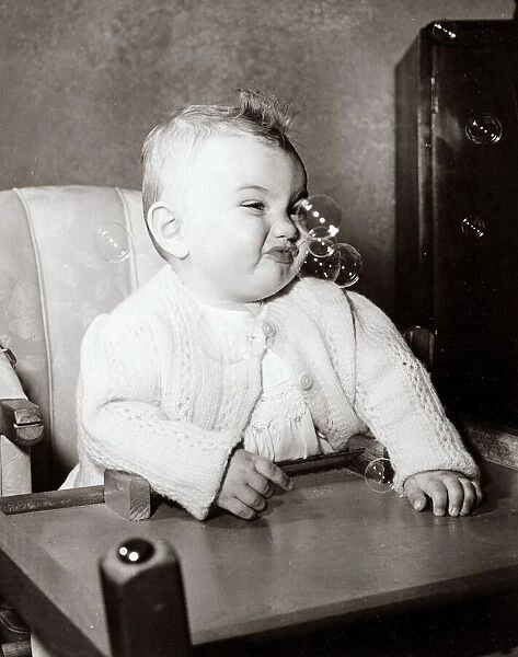 Baby enjoying bubbles in the air, circa 1950
