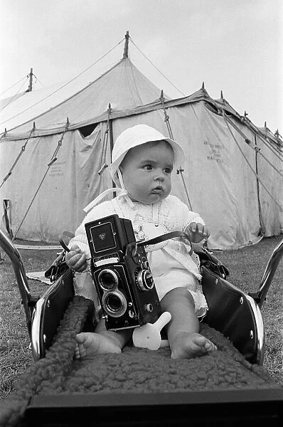 A baby sitting with a Rolleiflex camera at Skelton annual baby show. Circa 1973