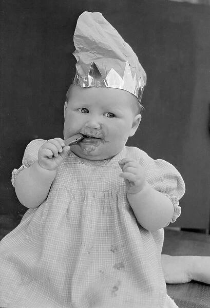 Baby wearing a party hat and eating a cadbury chocolate finger 31st October 1952