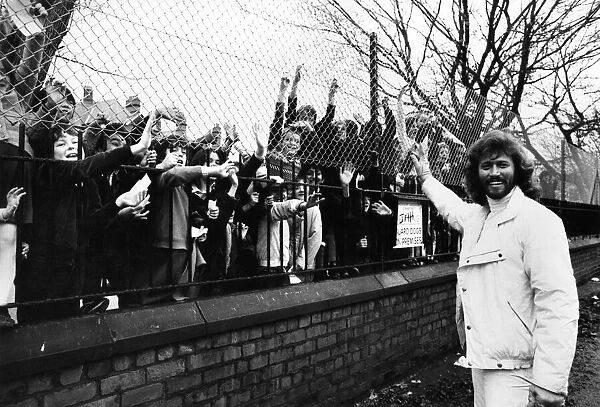 Barry Gibb of the Bee Gees pop group waves to children outside the gates of his former