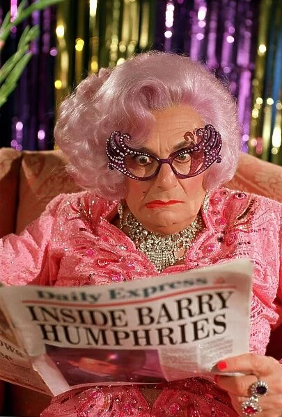 BARRY HUMPHRIES, CREATOR OF DAME EDNA EVEREDGE READING A MOCK UP DAILY EXPRESS