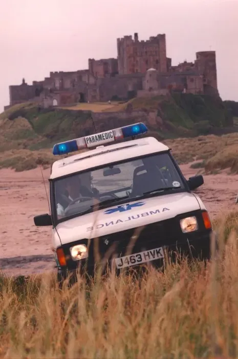 Framed Print : Beach combing - one of the new 4 wheel drive ambulances in action at Bamburgh Castle