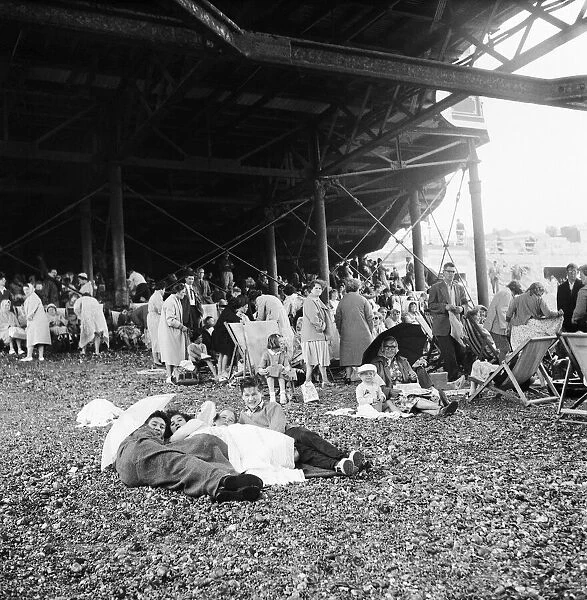 Beach scene Brighton, East Sussex. Crowds seek cover from a summer shower under the pier