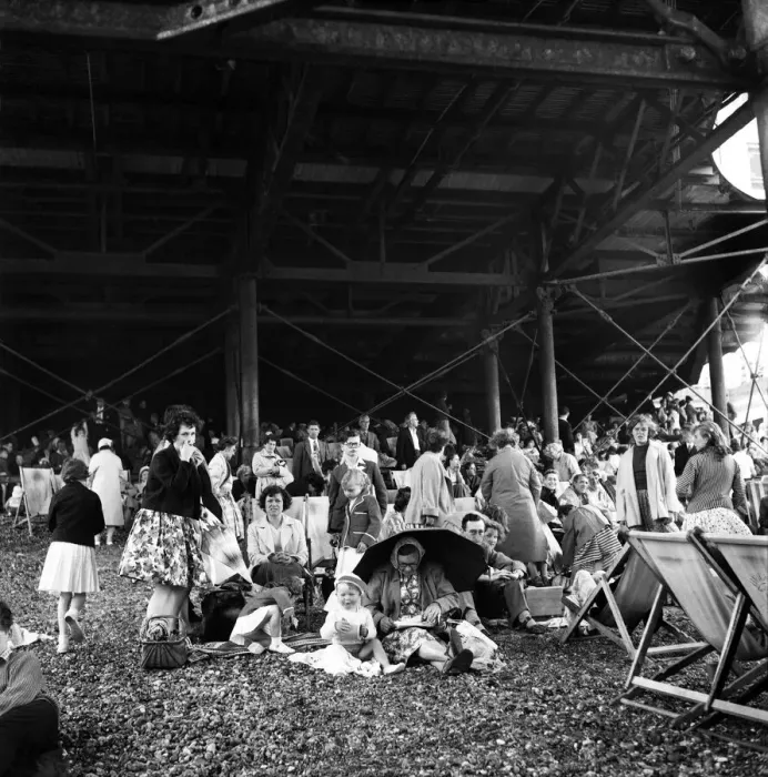 Framed Print : Beach scene Brighton, East Sussex. Crowds seek cover from a summer shower under the pier Framed Print : Beach scene Brighton, East Sussex. Crowds seek cover from a summer shower under the pier