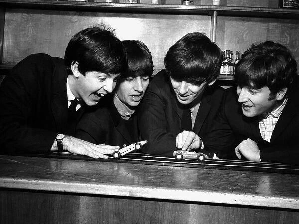 The Beatles in Coventry, amusing themselves with a miniature car race track before their