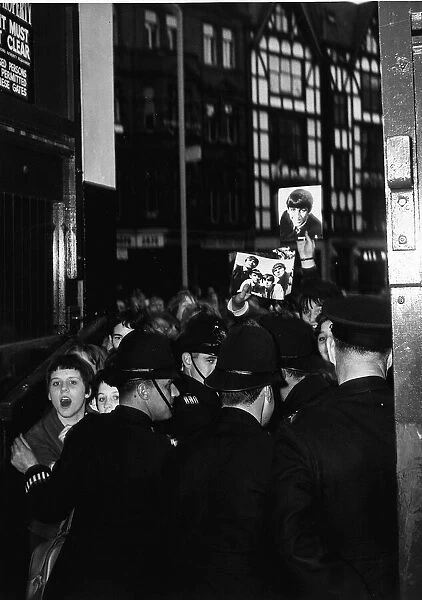 Beatles fans outside the London Palladium being held back from the band 13 October 1963