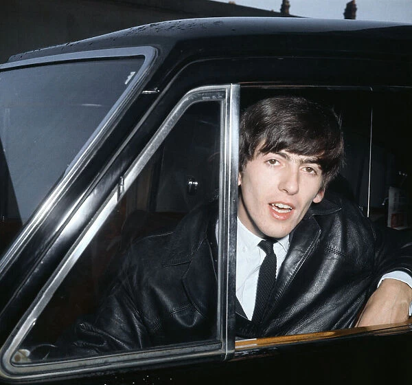 Beatles guitarist George Harrison leans out a car window during the band