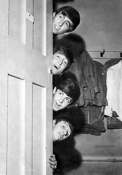 The Beatles peering out from behind their dressing room door before their appearance at