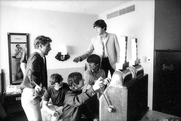 Beatles press officer, Derek Taylor, digs into his pocket for coins as the Beatles play