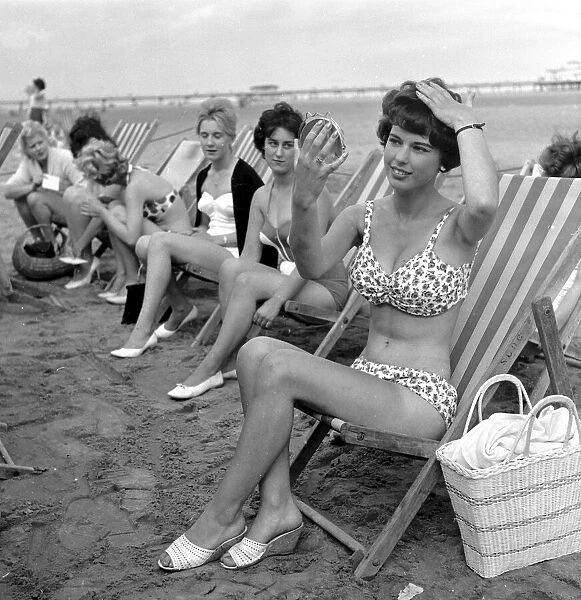 Beauty contest girls sitting in deck-chairs on the beach at Skegness putting on their