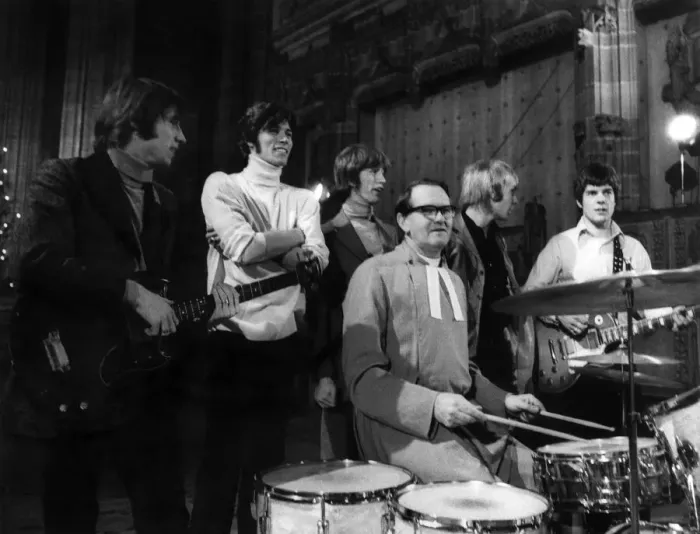 Framed Print : The Bee Gees pop group stand behind a vicar having a a go on the drums during rehearsals