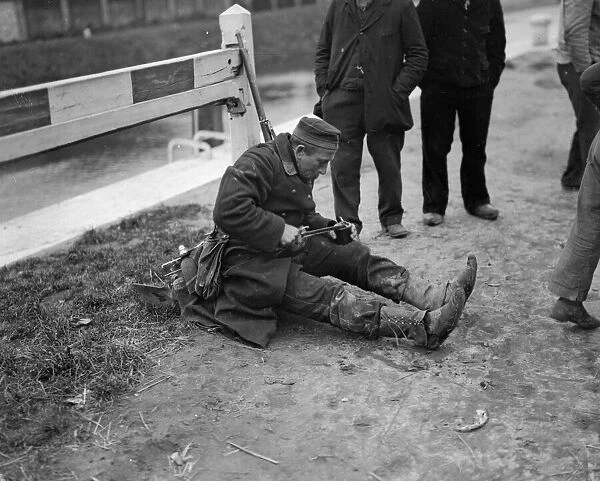A Belgian soldier tired out with much marching, sits down by the roadside for a meal
