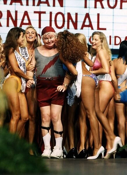 Benny Hill Comedian stands between bikini clad contestrants at a beauty competition