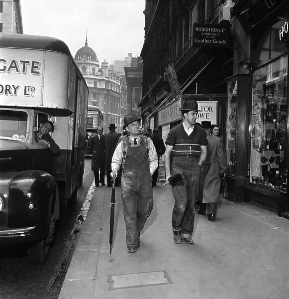 Bernie Crisp and friend stroll down a London Street wearing a bowler
