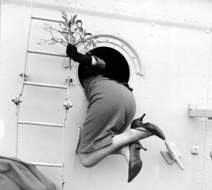 Framed Print : Beverley Janner holding mistletoe is pulled through a porthole by her sailor husband to Framed Print : Beverley Janner holding mistletoe is pulled through a porthole by her sailor husband to