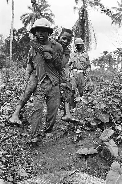 A Biafran soldier seen here carrying an injured comrade during the Biafra conflict