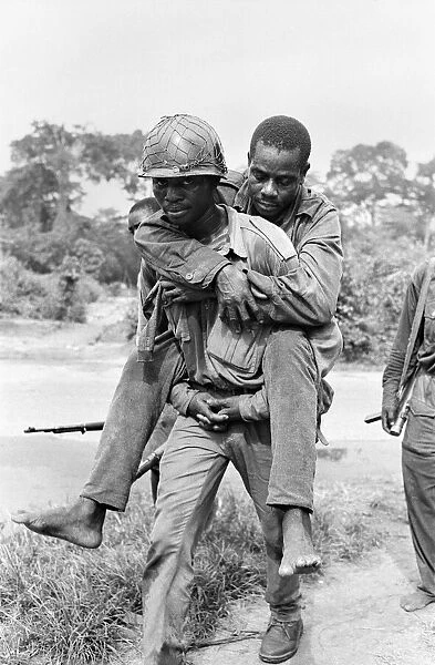A Biafran soldier seen here carrying an injured comrade during the Biafra conflict