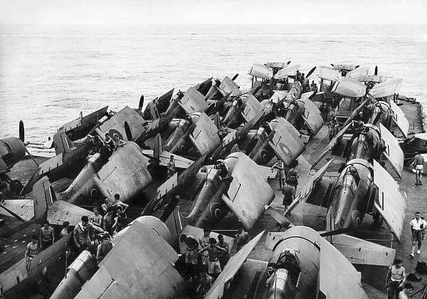 A big range of aircraft parked at the forward end of the flight deck of HMS Illustrious