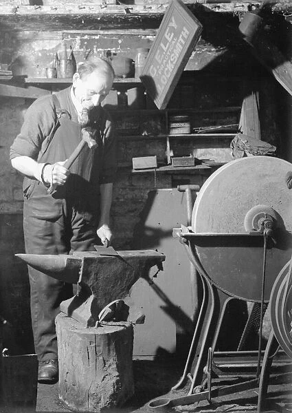 A Blacksmith works in his forge, hammering out a metal sheet on his anvil. Circa 1940