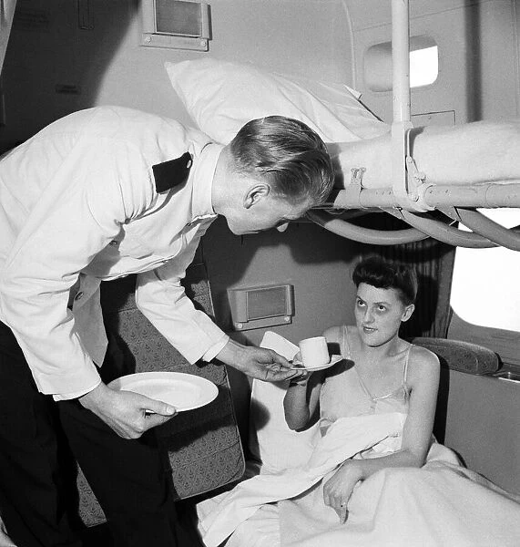 BOAC steward wakes a passenger on a BOAC flying boat service to the Far East with a cup