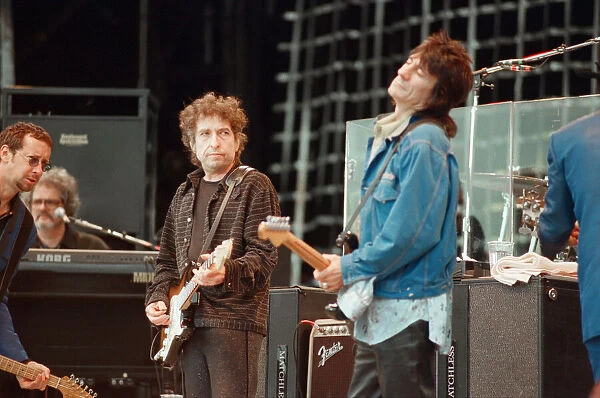 Bob Dylan (left in brown clothing) looks over at Ronnie Wood (in blue