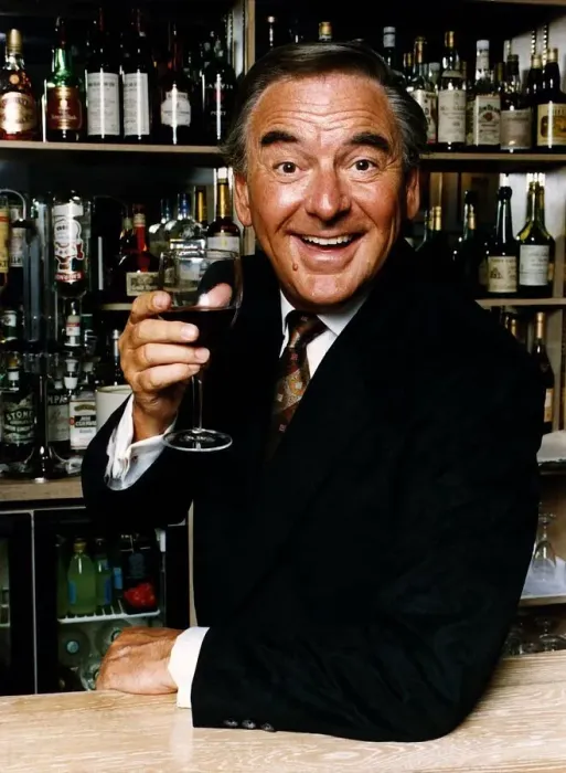 Framed Print : Bob Monkhouse raises a glass of wine standing behind a well stocked bar Framed Print : Bob Monkhouse raises a glass of wine standing behind a well stocked bar